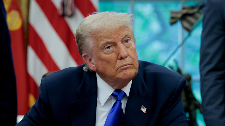 Donald Trump sits at a desk