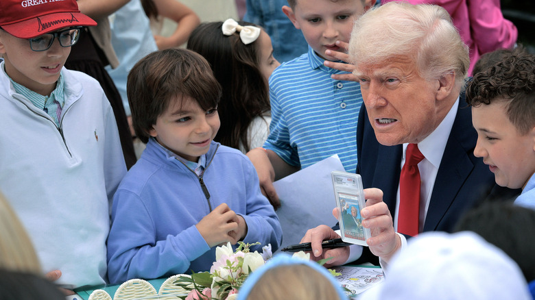 U.S. President Donald Trump holds a collectors card depicting the assassination attempt during the Easter Egg Roll on the South Lawn of the White House on April 21, 2025 in Washington, DC.