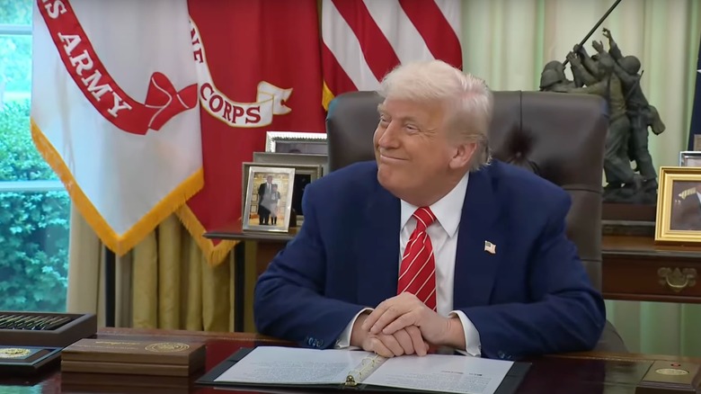 Donald Trump smiling at his desk in the Oval Office