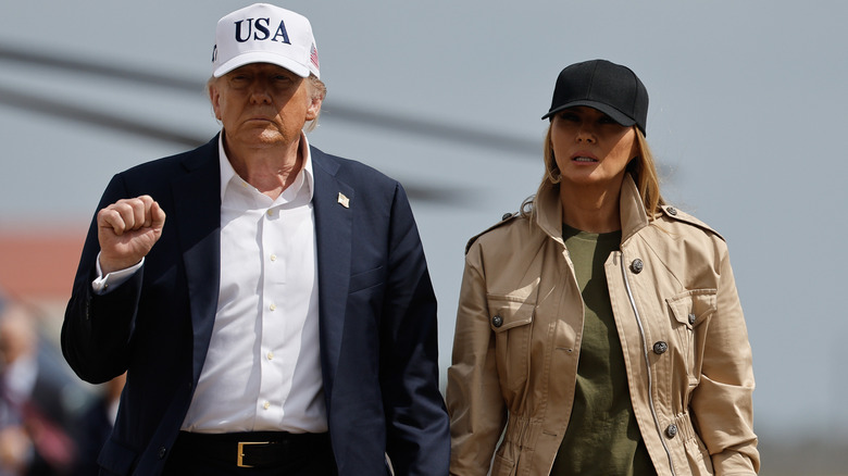 Donald Trump holding Melania Trump's hand as they walk across an Air Force base.