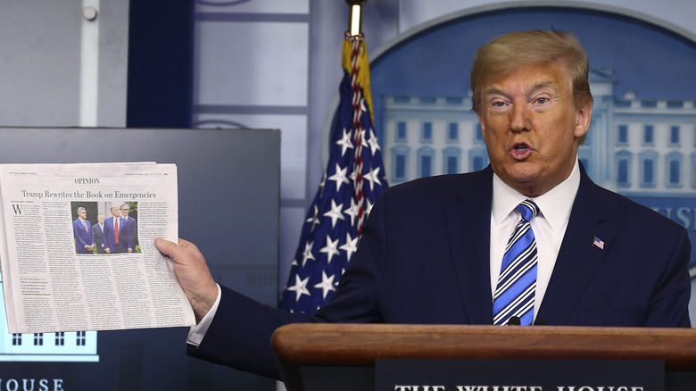Donald Trump holding a newspaper