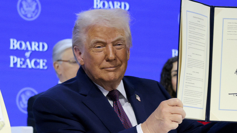image of Donald Trump holding up a document and smiling at the Davos event