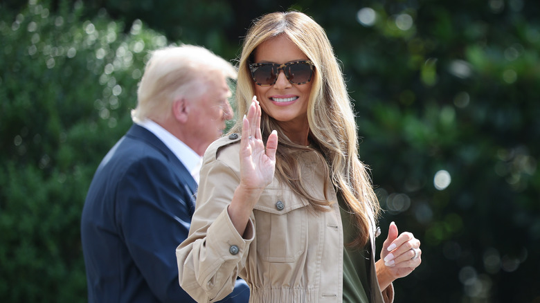 Melania Trump waves at the press as she walks next to Donald Trump outside the White House