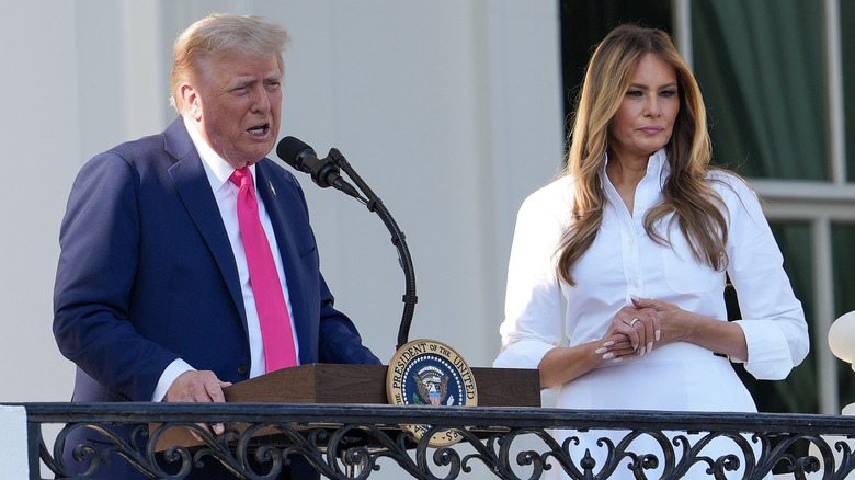 Donald Trump makes a speech while Melania stands next to him in white