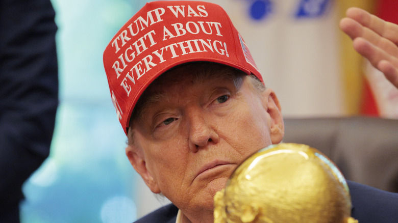 Donald Trump hiding behind a gold trophy