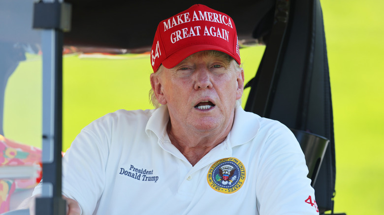 Donald Trump red MAGA hat president shirt in golf cart