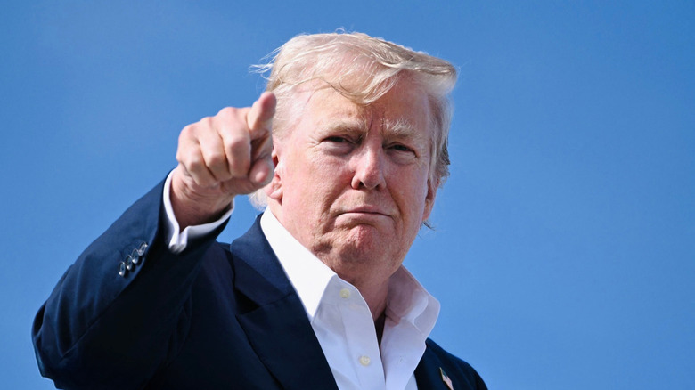 Donald Trump pointing while wearing a blue blazer and white collared shirt.