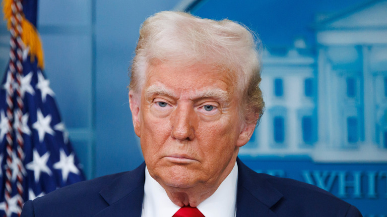 Donald Trump standing while wearing a suit and red tie.