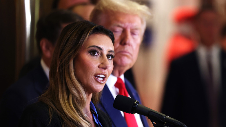 Alina Habba speaking into microphone next to Donald Trump