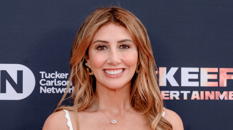 Alina Habba smiling in a white dress while attending the premiere of 'Line in the Sand' at the Mar-a-Lago club.