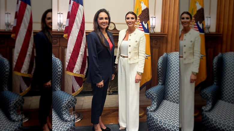 Alina Habba smiling in a white blazer and a pair of pants next to her friend who's wearing a navy blue blazer and pink shirt.