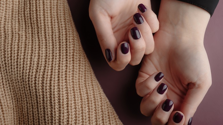 Dark purple nail polish on hands