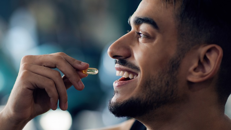 man smiling while taking pill