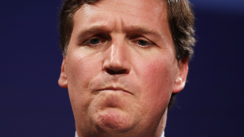 Tucker Carlson standing in front of a microphone