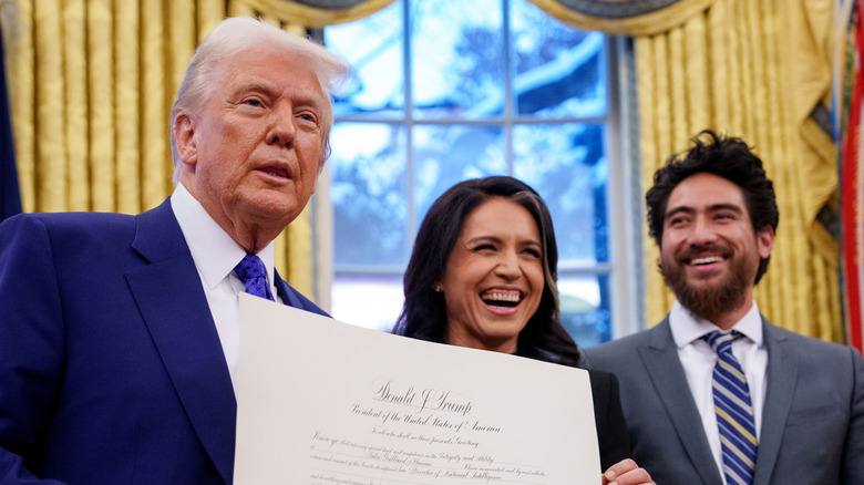 President Donald Trump stands with Tulsi Gabbard and her husband Abraham Williams in the Oval Office