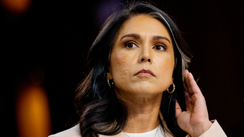 Tulsi Gabbard frowning with hand holding back hair