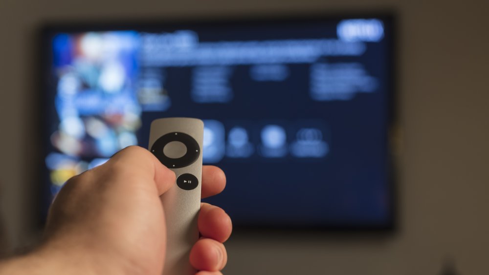 A hand pointing a remote at a TV 