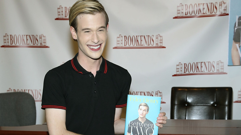 Tyler Henry smiling and holding his book at book signing