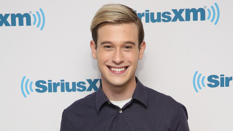 Tyler Henry smiling on SiriusXM step-and-repeat