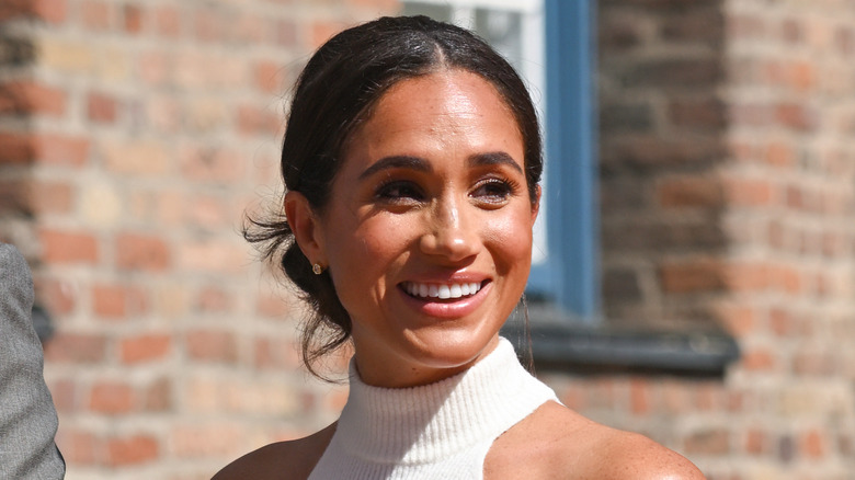 Meghan Markle, Duchess of Sussex holding her hand to her head