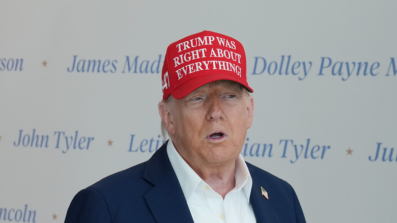 Donald Trump speaking in a red 'Trump was right about everything!' hat