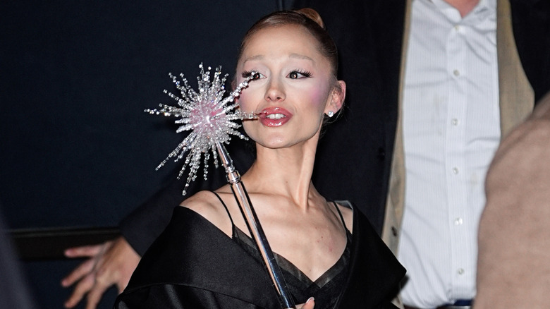 Ariana Grande wearing black and holding a wand