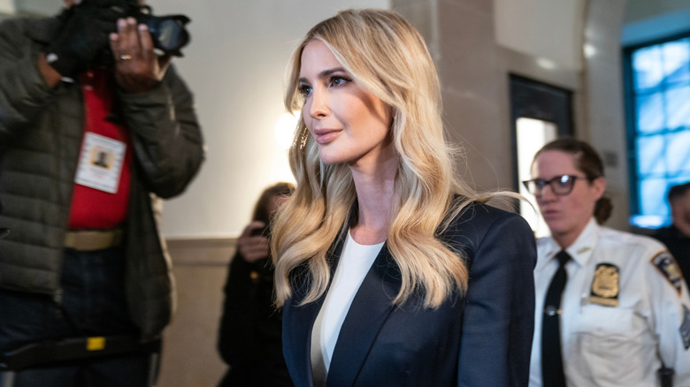 Ivanka Trump maintains a soft smile for passing cameras as she's followed by security
