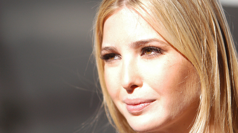 Ivanka Trump squinting into the bright lights while posing for cameras at an event