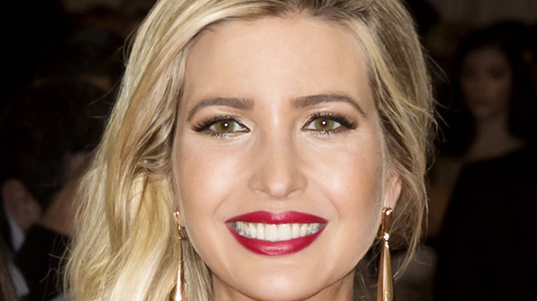Ivanka Trump smiles for the camera with a bold red lip and side swept blonde hair