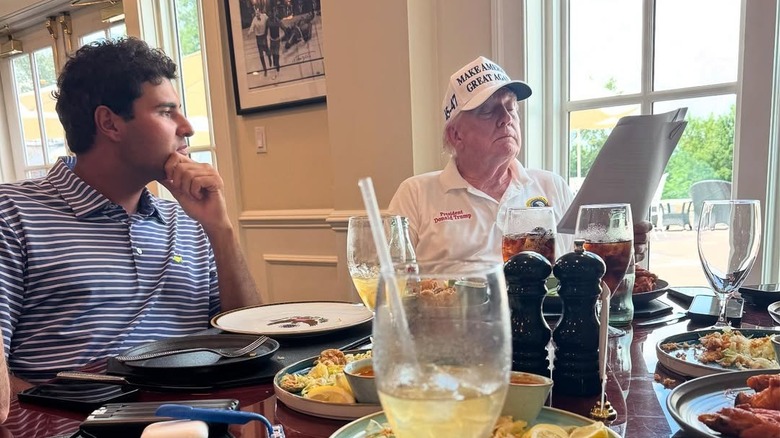 Eugenio Chacarra and Donald Trump sit at a table full of food
