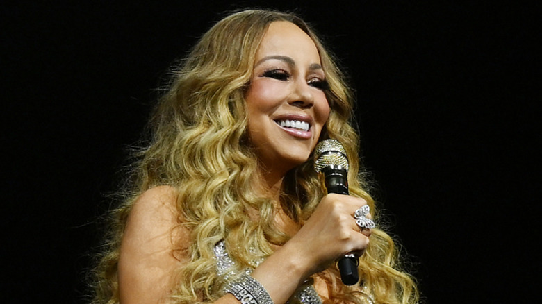 Mariah Carey performing with a microphone in her right hand