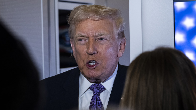 Donald Trump sticks his lower lip out while speaking to the press on Air Force One.