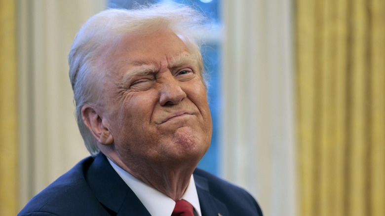 Donald Trump lifts his chin and scrunches up his face in the Oval Office.