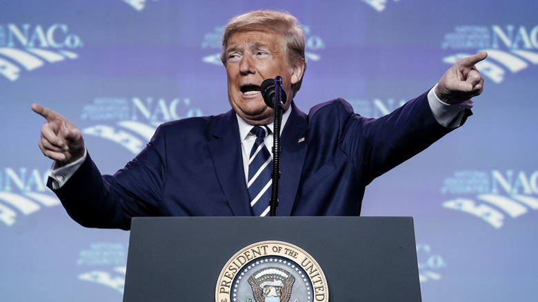 Donald Trump looks distressed and points in two different directions while speaking at the National Association of Counties Legislative Conference.