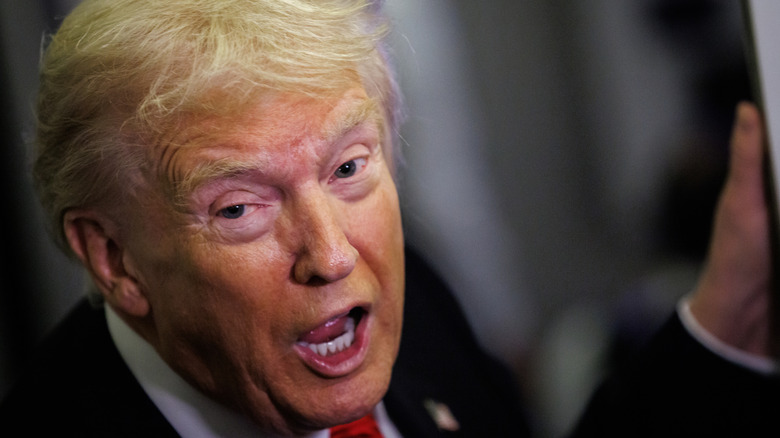 A close-up of Donald Trump with his mouth open and pink skin around his eyes on Air Force One.