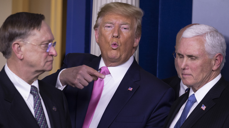 Donald Trump puckers his lips and points at Mike Pence in the White House press briefing room.
