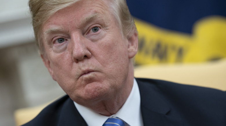 Donald Trump tightly purses his lips and raises his eyebrows.