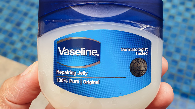 Hand holding a jar of vaseline