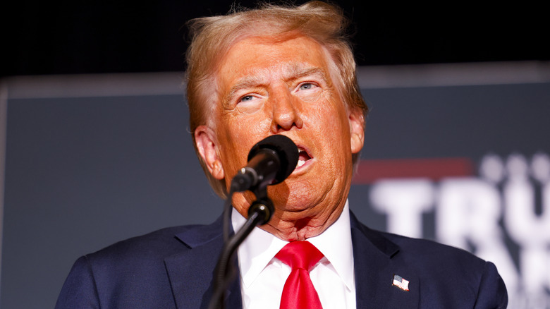 Donald Trump's skin looks bright orange as he speaks into a microphone.