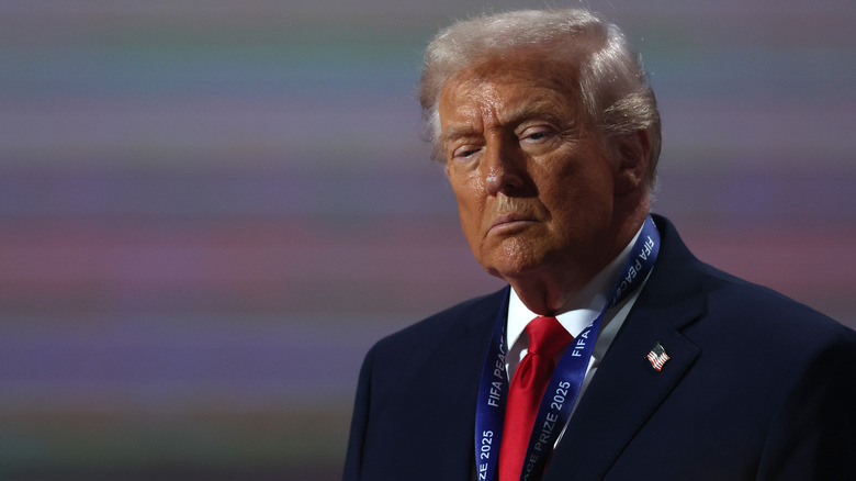 A sweaty-faced Donald Trump squints and looks downcast while wearing his FIFA Peace Prize medal.