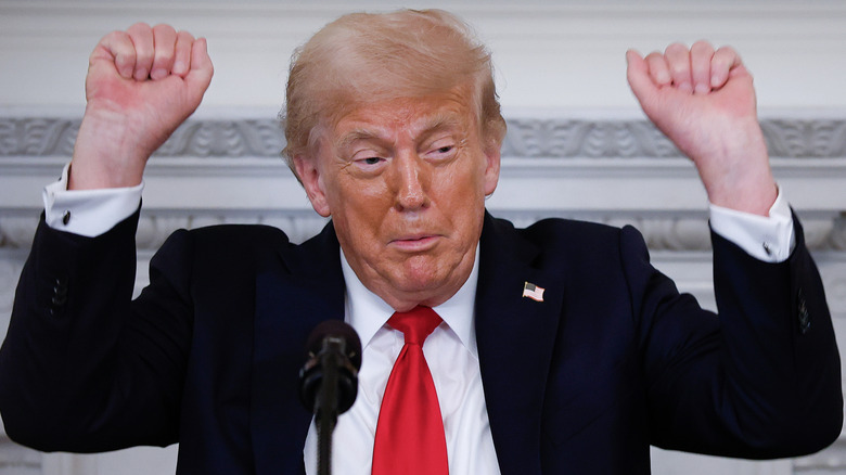 Donald Trump raises his fists and squints.