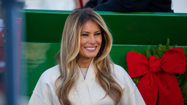 Melania Trump looking left smiling Christmas bow background