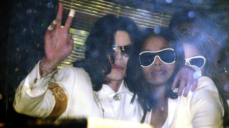 Michael Jackson waving while embracing Janet Jackson.