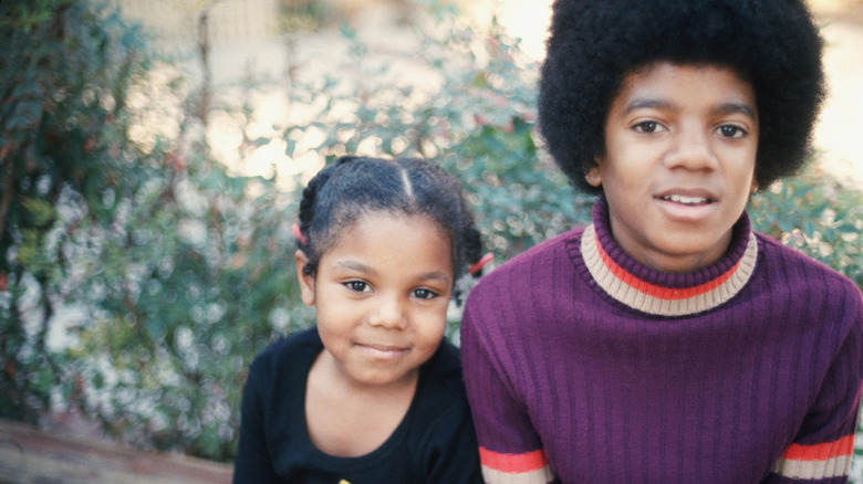 A very young Janet Jackson smiling next to a teenage Michael Jackson.
