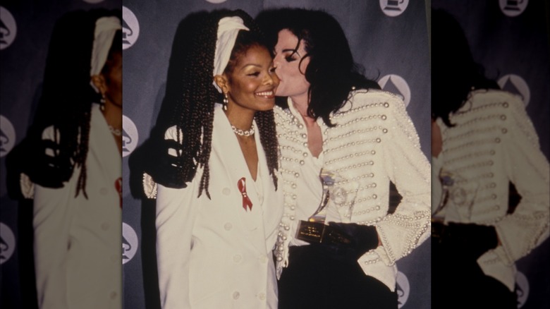 Michael Jackson kissing a smiling Janet Jackson on the cheek.