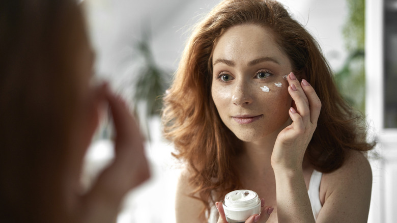 woman applying skincare to face