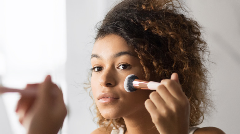 Woman applying blush in mirror