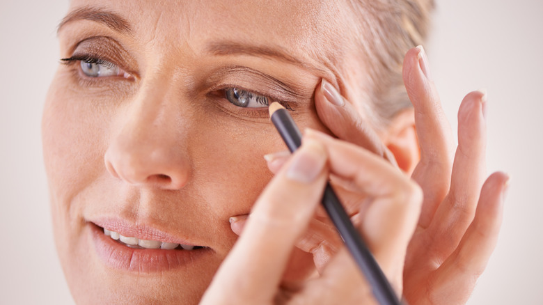 Woman applying pencil eyeliner