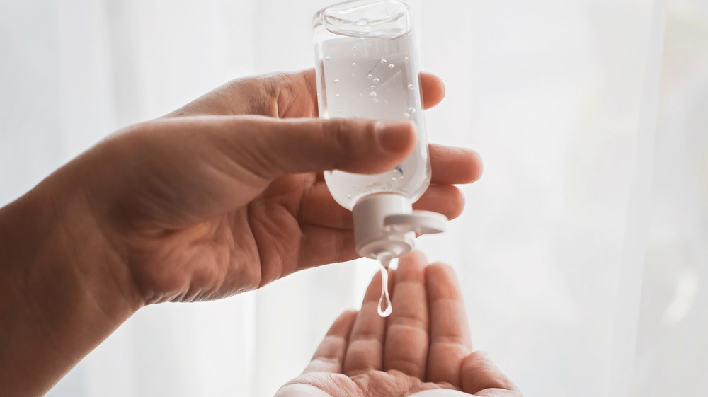 Person squeezing hand sanitizer from a bottle
