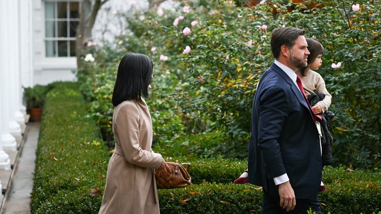 JD Vance carries his daughter, while Usha Vance follows behind